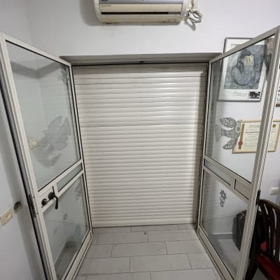 תריס גלילה לבן סגור בין דלתות זכוכית פתוחות