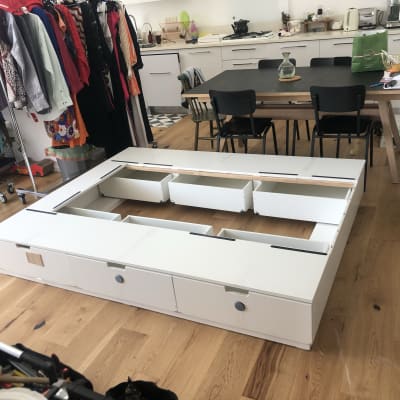 מסגרת מיטה לבנה עם מגירות פתוחות על רצפת עץ