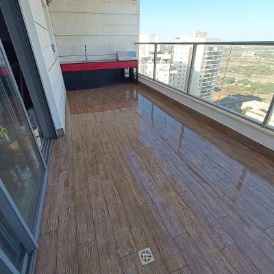 מרפסת עם רצפת עץ חדשה ומעקה זכוכית