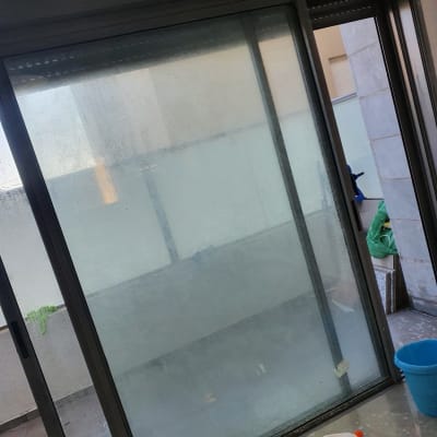 חלון זכוכית מלוכלך עם דלי כחול ומטלית ירוקה