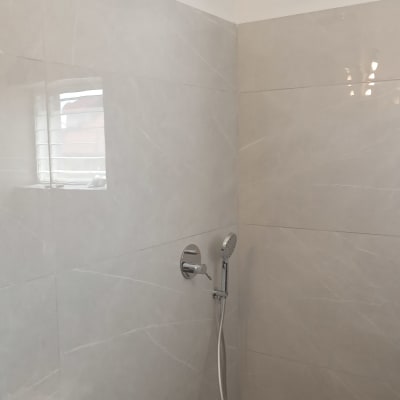 מקלחת חדשה עם אריחים אפורים וראש מקלחת עגול