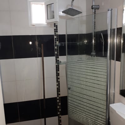 חדר אמבטיה עם מקלחון, חלון קטן ומגב אדום