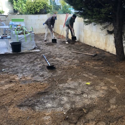 שני אנשים חופרים באדמה עם אתים בגינה