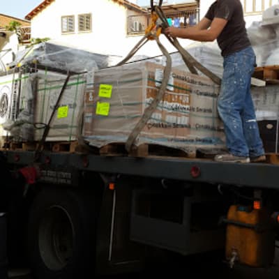 אדם מעמיס חומרי בנייה על משאית עם מנוף