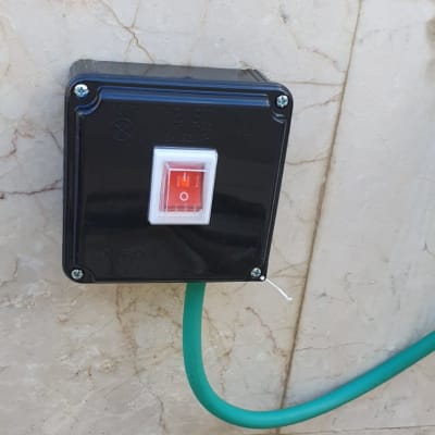 מתג חשמלי שחור עם כבל ירוק על קיר