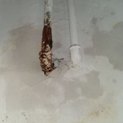 צינור חלוד עם נזילה על קיר לבן