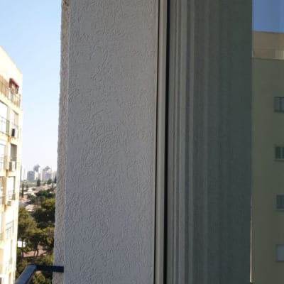 קיר חיצוני עם טיח מחוספס ליד חלון זכוכית