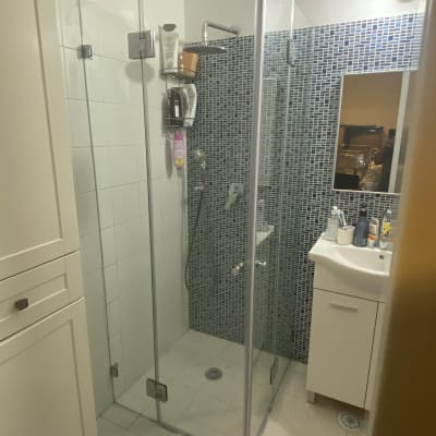 מקלחון זכוכית עם מדף מוצרים ומקלחת יד