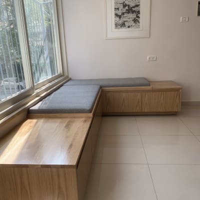 ספסל עץ עם כריות אפורות ליד חלון