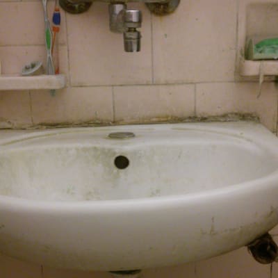 כיור עם ברז חלוד וצנרת מתחת