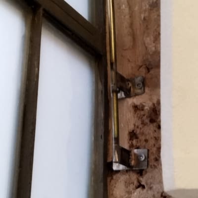 מסגרת חלון מתכתית עם מוט תמיכה על קיר עץ