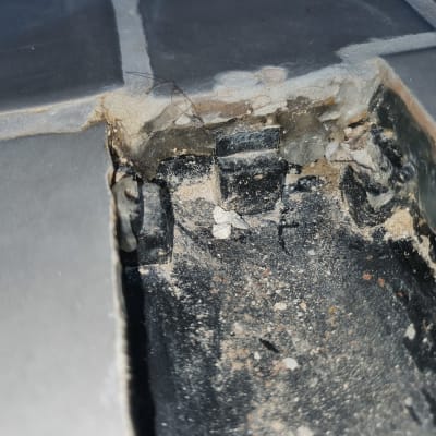 אריח שבור עם סימני רטיבות וחול מתחתיו