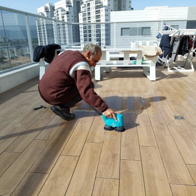 אדם מנקה רצפה עם מכשיר חשמלי כחול