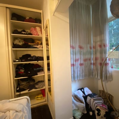 ארון בגדים פתוח עם בגדים מקופלים, וילון ליד חלון