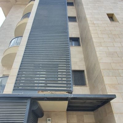 רשת מתכת על קיר בניין למניעת כניסת יונים