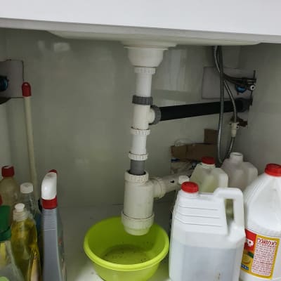 כיור עם צנרת פלסטיק, קערה ירוקה מתחת לצינור