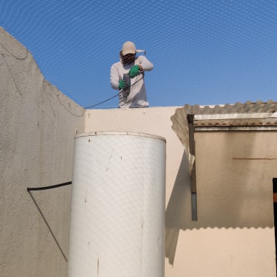 אדם מתקין רשת למניעת כניסת יונים