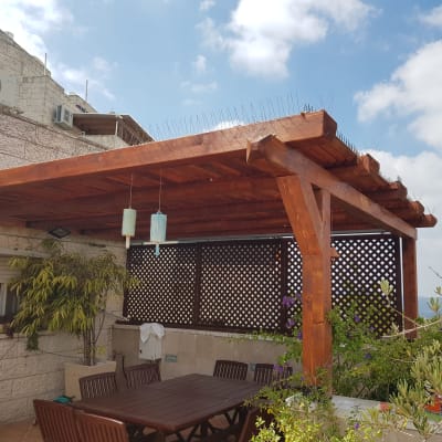 פרגולה מעץ עם שולחן וכיסאות בגינה