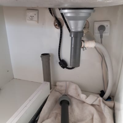 כיור עם צינורות ניקוז וכלי עבודה מתחת לכיור