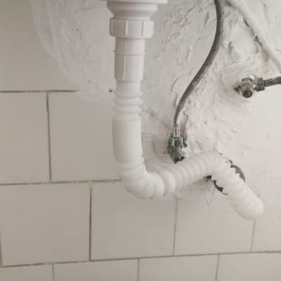 צינור ניקוז לבן מתחת לכיור עם חיבורים