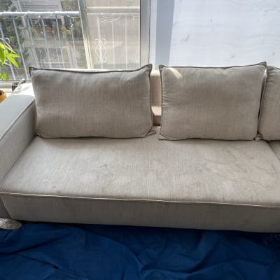 ספה אפורה עם כריות על רקע חלון