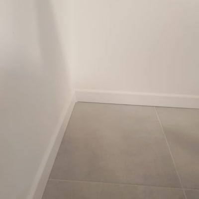 פינת קיר עם ריצוף אפור ולוח בסיס לבן