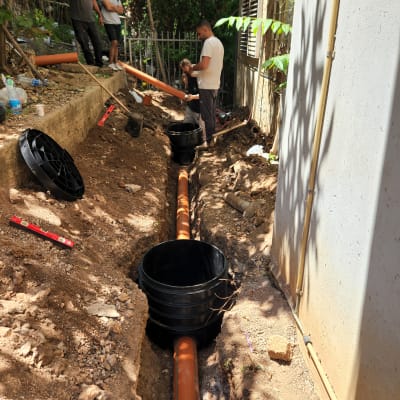 עבודת אינסטלציה עם צינורות כתומים וחפירה באדמה