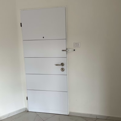 דלת לבנה עם ידית מתכת ובריח עליון