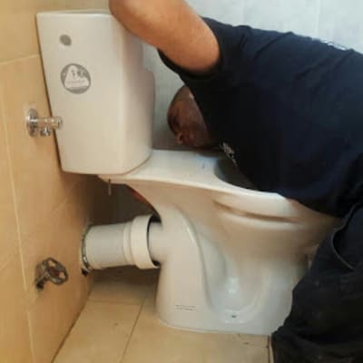 אדם עובד על תיקון אסלה בחדר אמבטיה