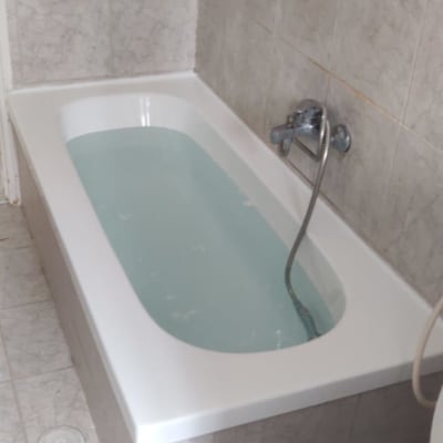 אמבטיה מלאה מים עם ברז ומקלחת יד