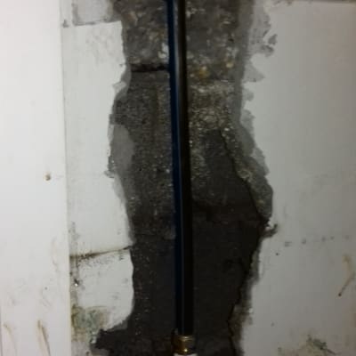 צינור מים מותקן בקיר שבור עם חיבורי מתכת