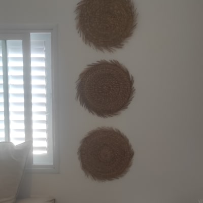 שלושה קישוטי קיר עגולים קלועים תלויים על הקיר