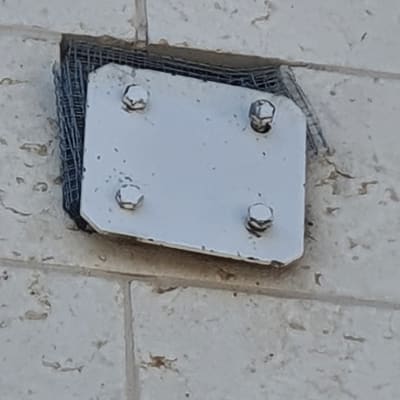 לוח מתכת עם ברגים על קיר אבן