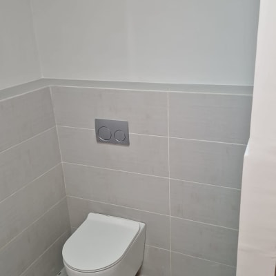 אסלה תלויה על קיר עם אריחים אפורים