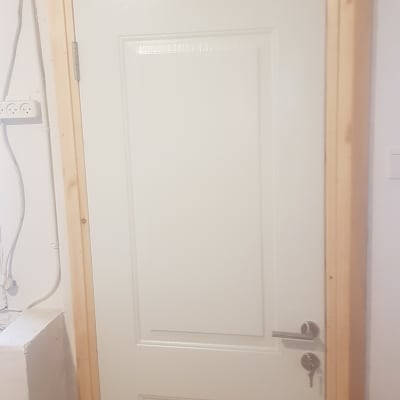 דלת לבנה עם מסגרת עץ ומנעול כסוף