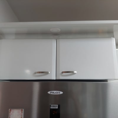 ארון מטבח לבן עם ידיות מתכת מעל מקרר