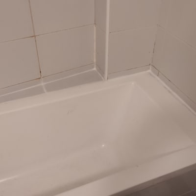 אמבטיה עם ברז מתכת על קיר אריחים לבנים