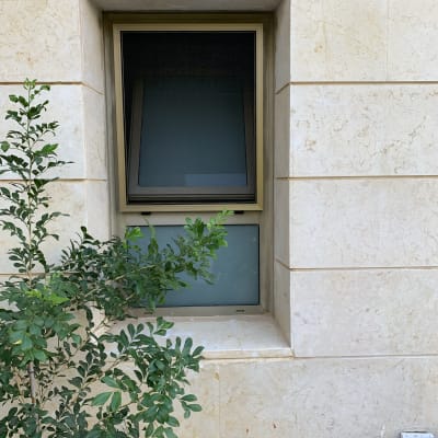 חלון אלומיניום עם מסגרת חומה בקיר אבן