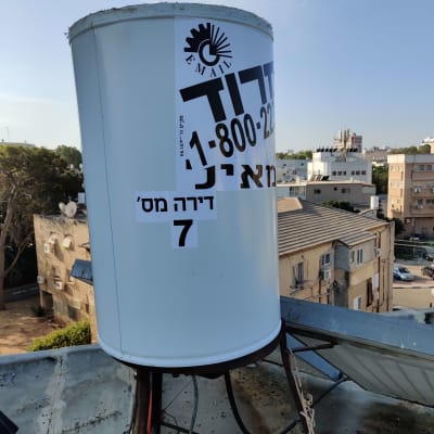דוד שמש על גג עם מדבקה ומספר טלפון