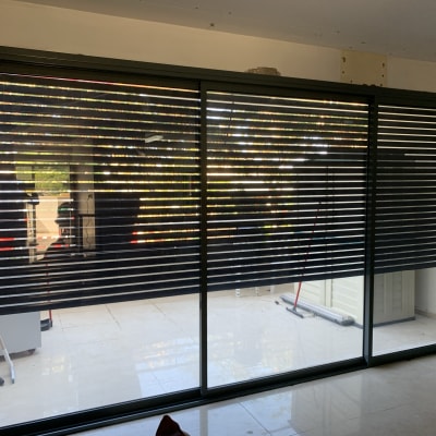 תריסי אלומיניום כהים על חלון זכוכית גדול