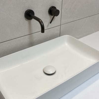 כיור מלבני עם ברז שחור על קיר אריחים