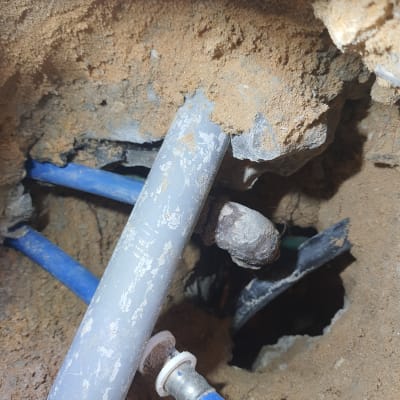 צינורות פלסטיק כחולים ואפורים בתוך קיר עפר