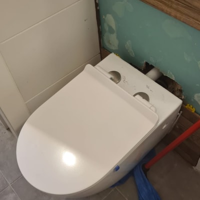 אסלה מותקנת עם מגבת כחולה וכלי עבודה אדום