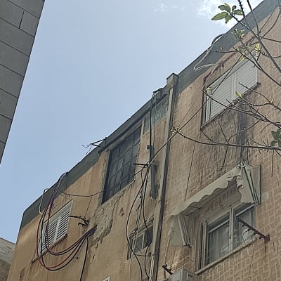 בניין עם חלונות, תריסים וחוטי חשמל חיצוניים