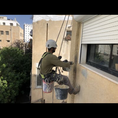 אדם על חבלים אוטם קיר חיצוני עם מלט