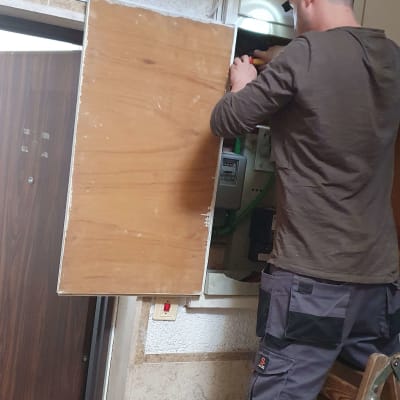 חשמלאי עובד על לוח חשמל עם מברג ביד