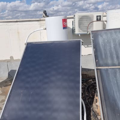 דוד שמש עם קולטים על גג תחת שמיים כחולים