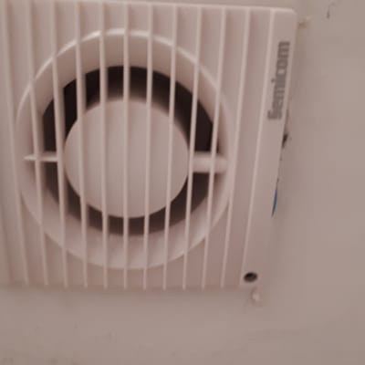 מאוורר קיר חשמלי מותקן על קיר לבן
