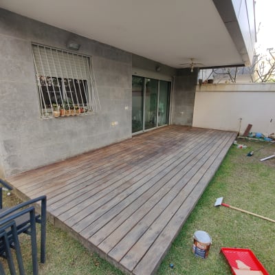 מרפסת עץ עם כלי צביעה ומברשת על הדשא