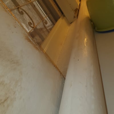 צינור לבן ליד חלון עם סורג מתכת